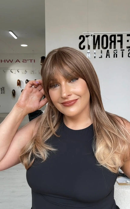light golden brunette ombre hair, medium length straight hair wig with middle part and fringe, soft blended colour for a natural sun-kissed look.