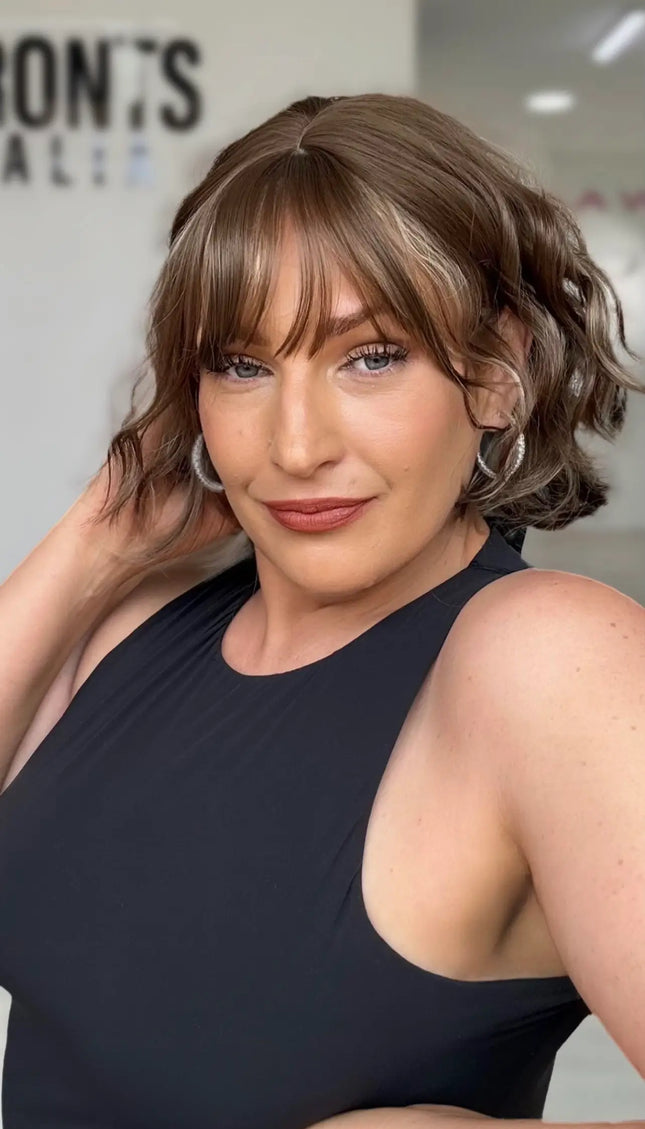 a soft wavy light brunette short bob with a soft fringe and middle part, blonde highlights througout.
