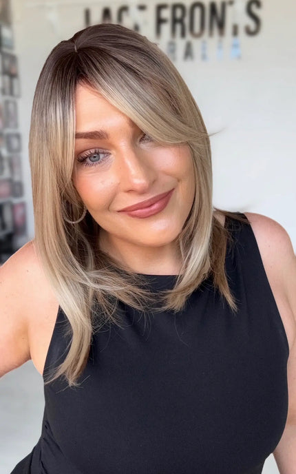 multi toned blonde layered long bob with curtain bangs and layers around face. multi toned slight warm blonde with soft brunette shadow root.