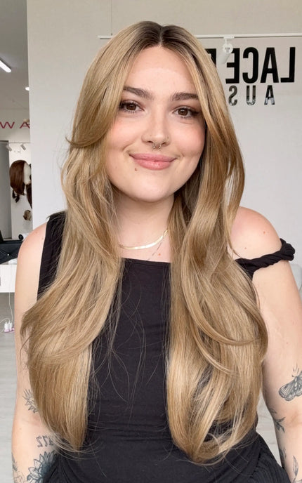 long length hair with middle part and long curtain bangs parted to the side, dark honey blonde hair with a shadow root for dimension, natural looking hairline.