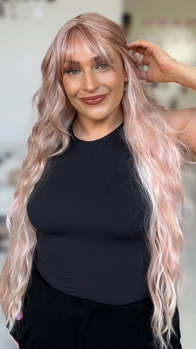 long length wavy pink hair wig with middle part and long wispy fringe, light layers around face and fringe. light pink pearly hair.