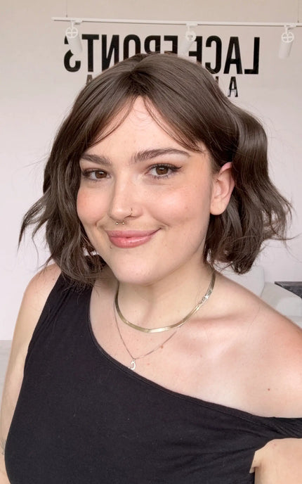 a wavy brunette , short length bob with a middle part and light fringe parted to the side. cool toned brunette.