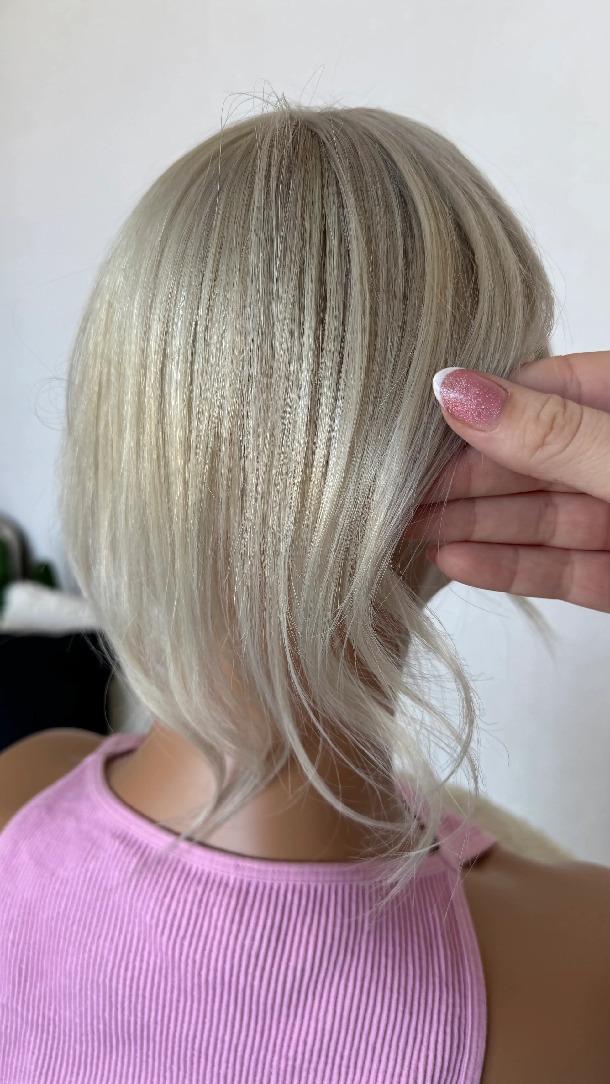 blonde topper from behind 12 inch length holding the hair.