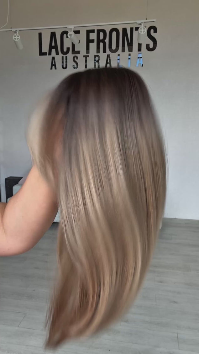 multi toned warm blonde with darker root for dimension, long bob length wig with soft layers for movement, long curtain bang fringe parted to the side with a middle part, heat safe hair with glueless wig cap