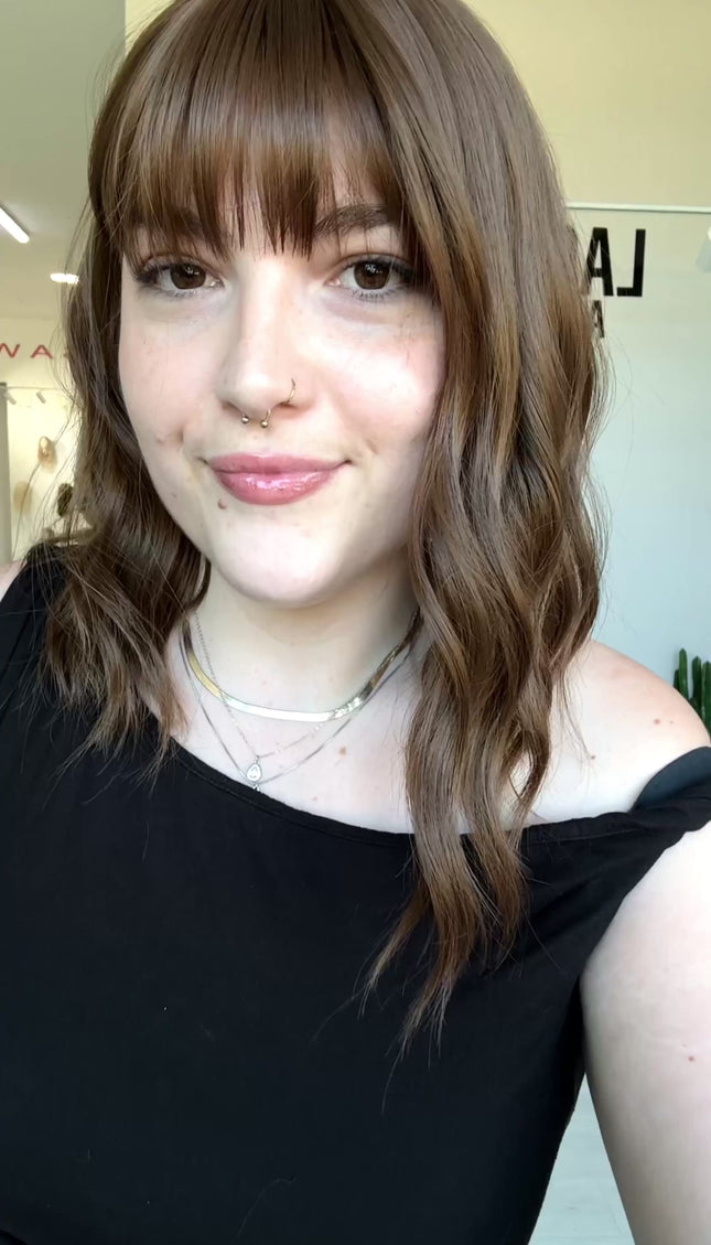wavy brunette hair with middle part and fringe.