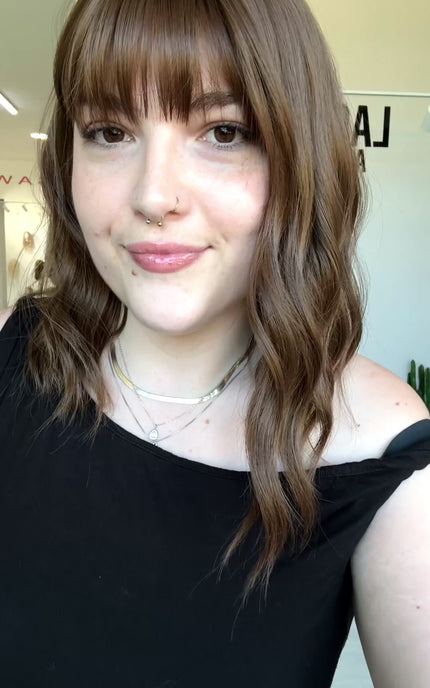 wavy brunette hair with middle part and fringe.