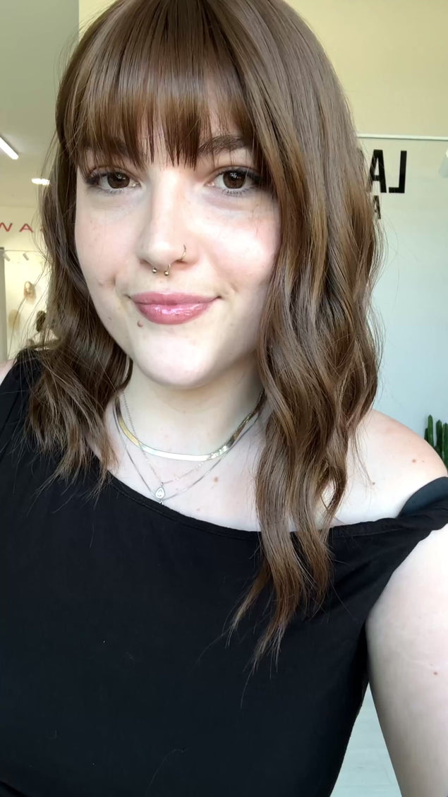wavy brunette hair with middle part and fringe.