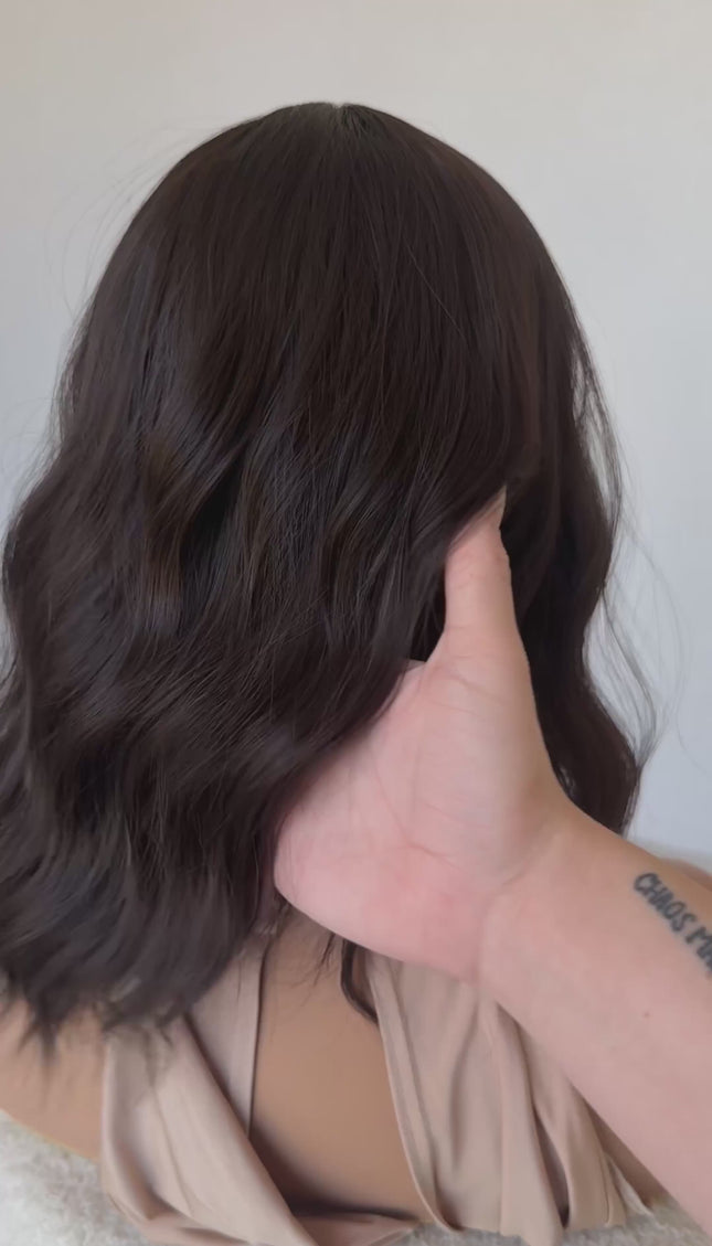 dark wavy brunette synthetic wig with heat safe hair and glueless cap.