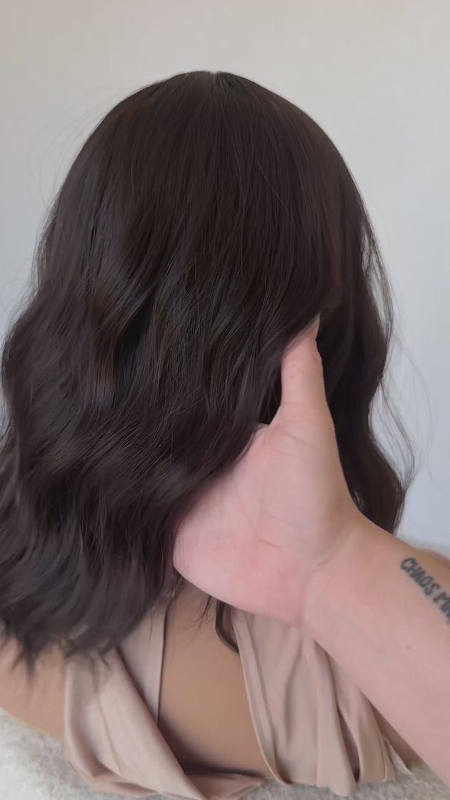 dark wavy brunette synthetic wig with heat safe hair and glueless cap.