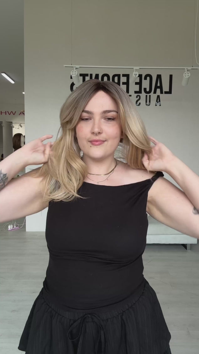 a layered warm blonde ombre hair with a soft brunette root, middle part and curtain bangs parted to the side, can be worn up or down. can be heat styled, can be worn glueless.