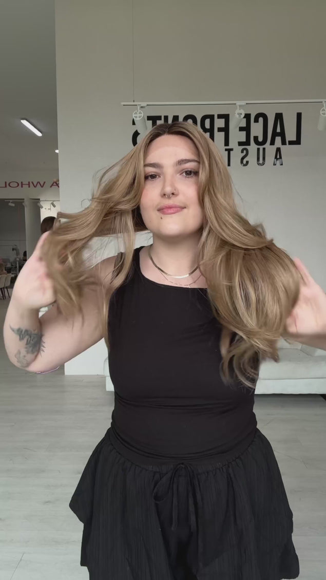 long length layered honey blonde hair with dark bruentte shadow root and middle part, long bouncy layers with salon blowdry styling.