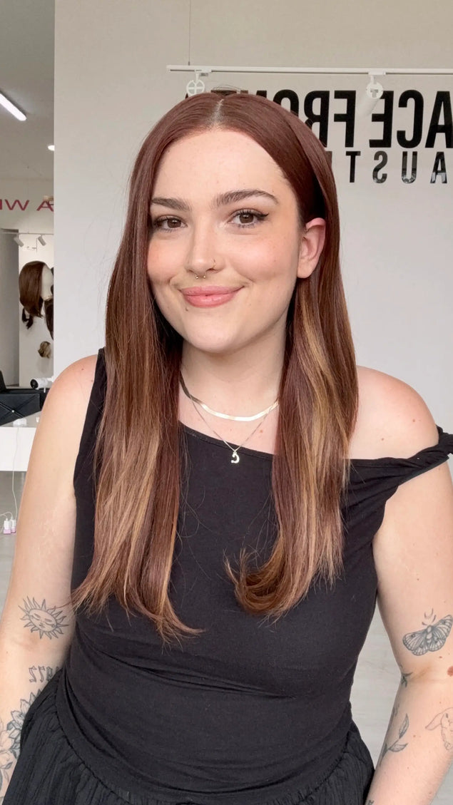 hair tucked behind ear with a middle part, long red copper synthetic hair that can be heat styled, middle part can be changed.