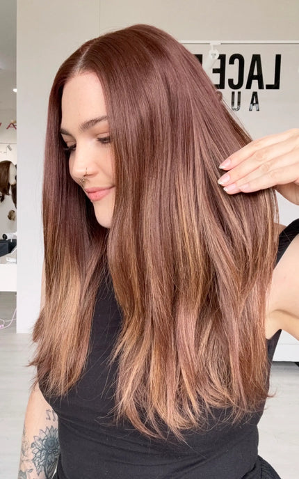 right side view holding red copper straight hair, heat safe synthetic wig with an interchangeable part.