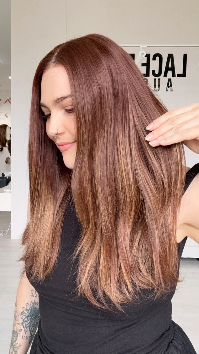 right side view holding red copper straight hair, heat safe synthetic wig with an interchangeable part.