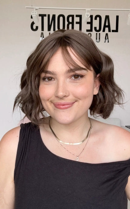 a short length wavy brunette bob, neutral toned brunette, no warmth, middle part with wispy fringe and heat safe hair.