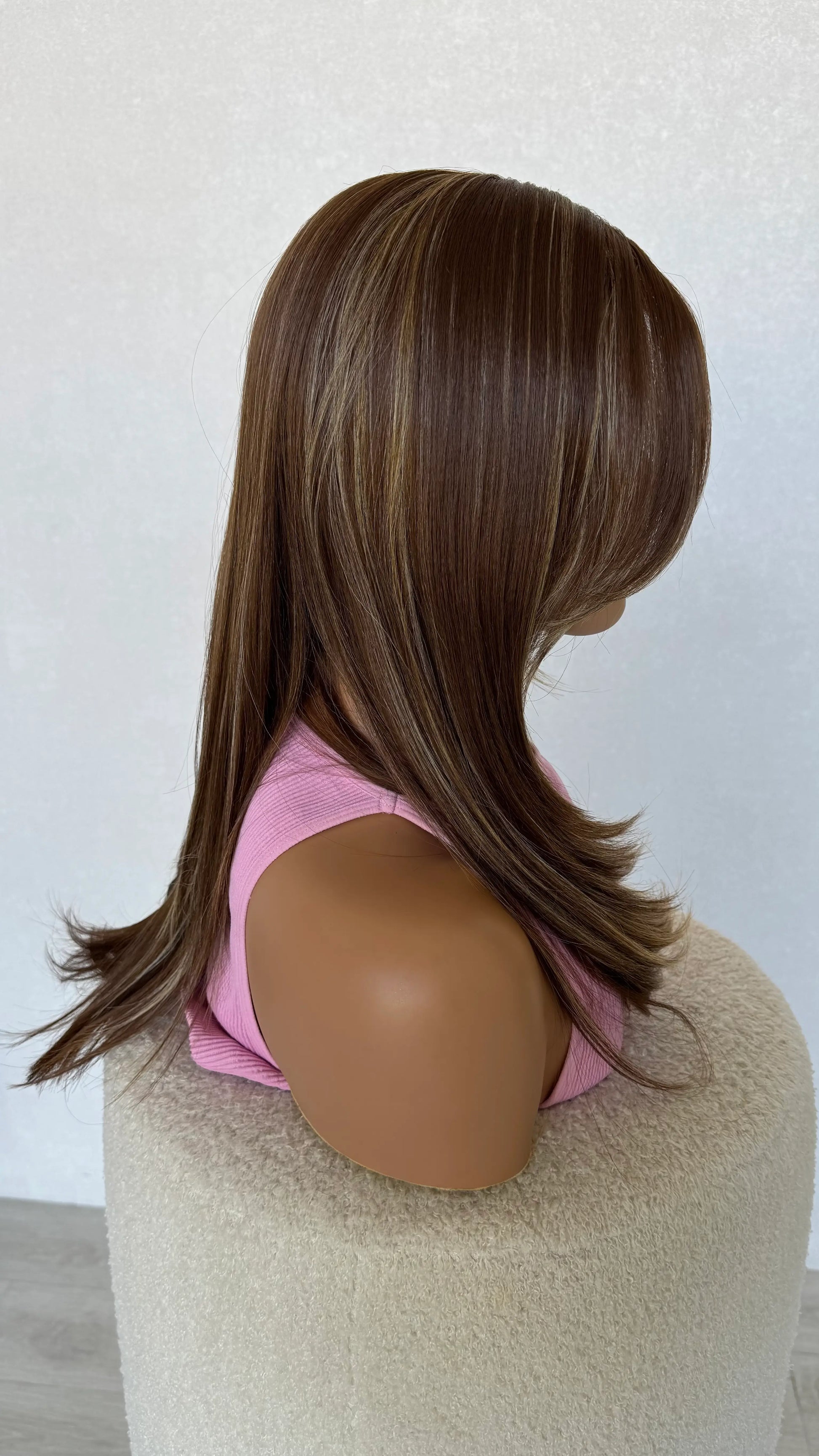 cinnamon brunette with warm highlights side view, showing haircut and length at back of head.