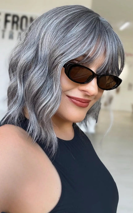 side view showing slight platinum ash highlights through silvery grey wavy hair, middle part with soft fringe.