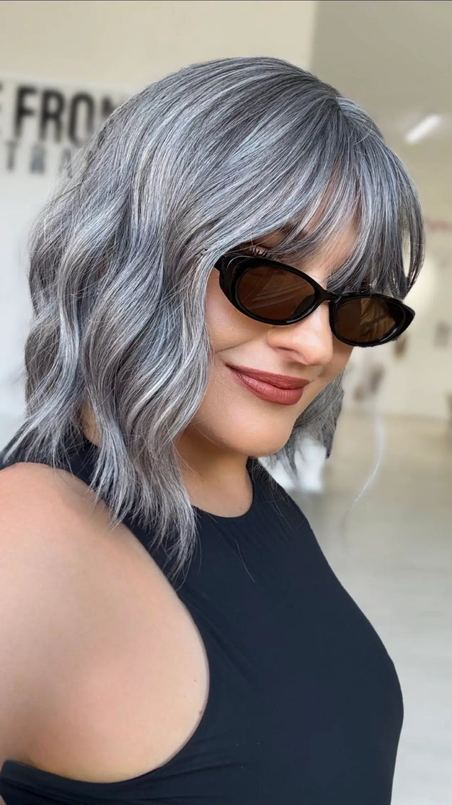 side view showing slight platinum ash highlights through silvery grey wavy hair, middle part with soft fringe.