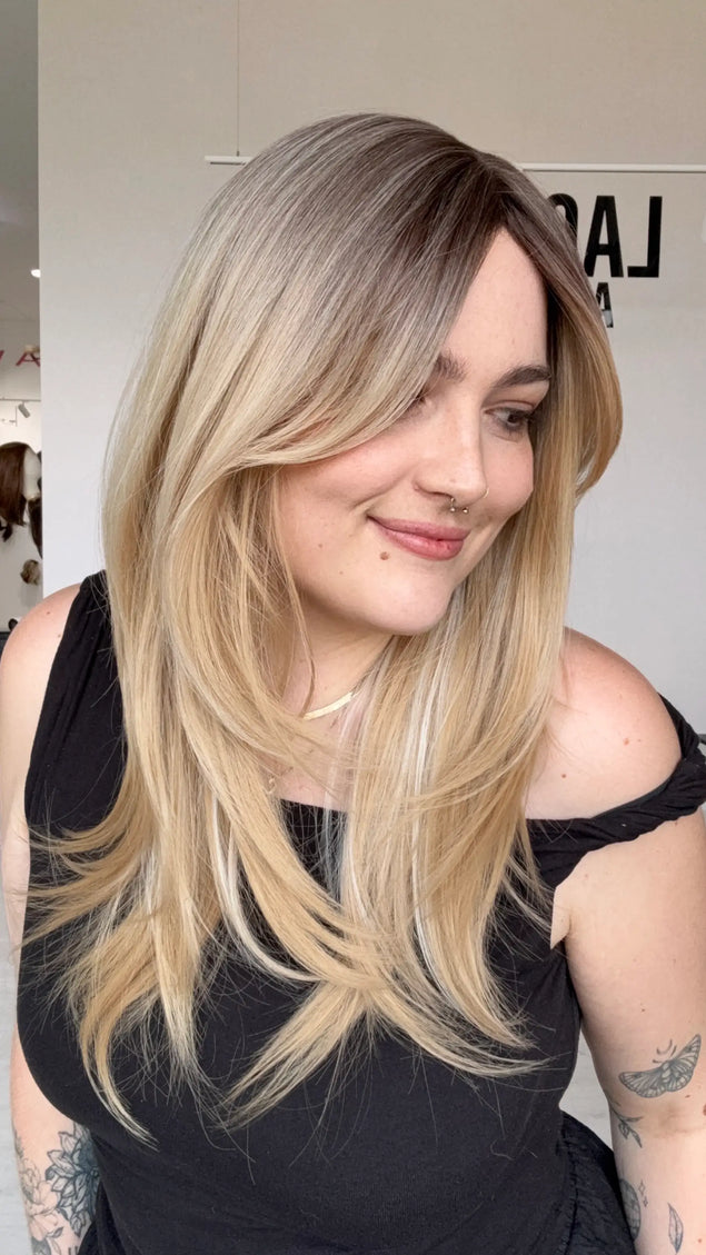 an easy to wear, layered blonde hair synthetic wig. for hairloss, alopecia, chemotherapy. a soft brunette root blending into a dimensional warm blonde range of colours.