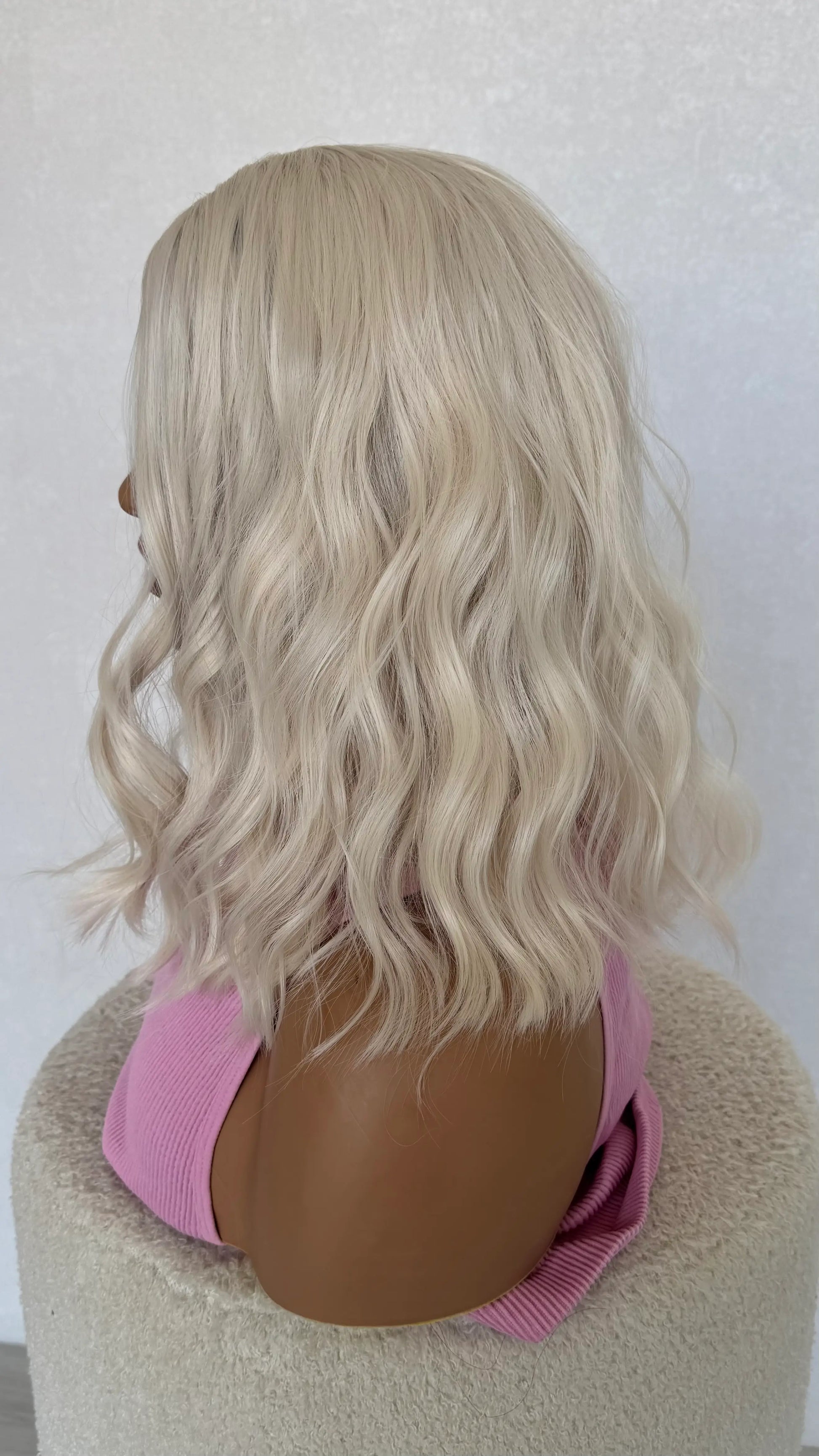 Blonde wig on a mannequin head with a pink top against a white background