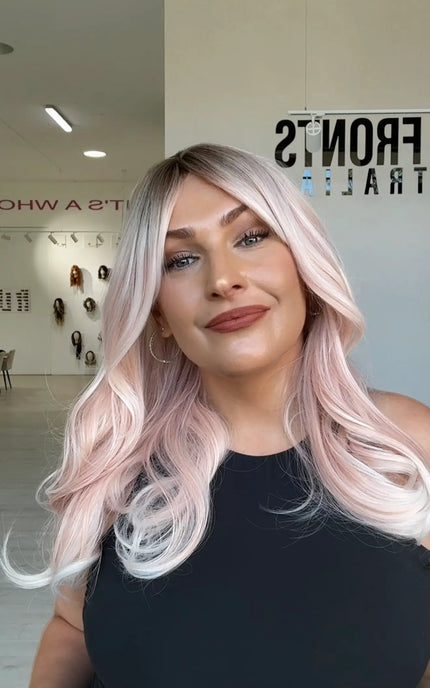soft pastel pink hair, mid length hair that comes to mid chest, has a slight darker shadow root for added dimension, fringe parted to the side.