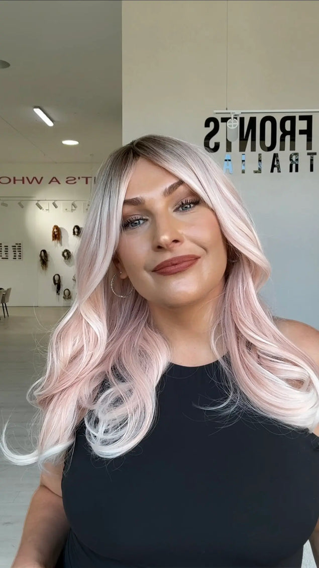 soft pastel pink hair, mid length hair that comes to mid chest, has a slight darker shadow root for added dimension, fringe parted to the side.
