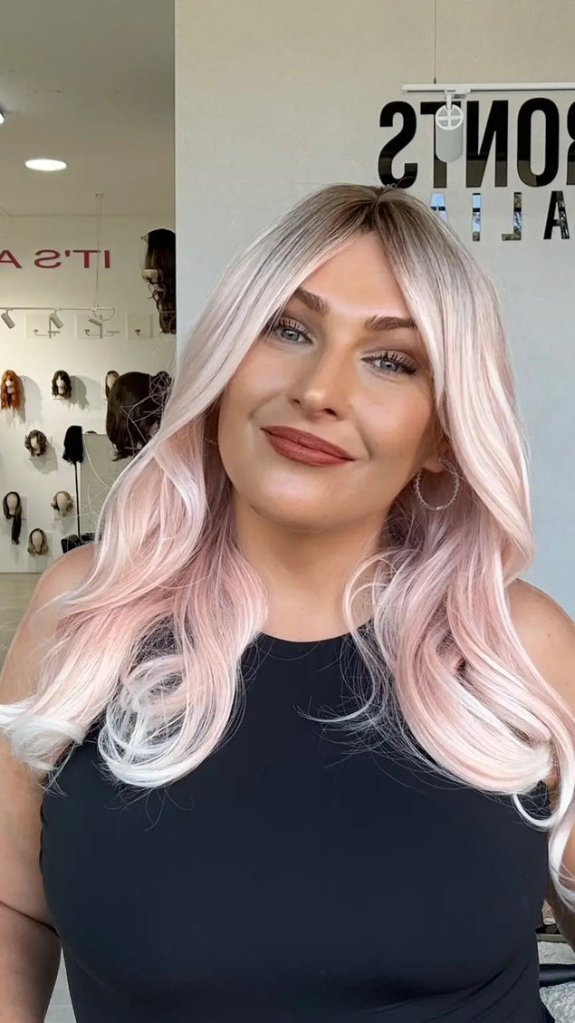 soft pastel pink hair with long curtain bang layers, a middle part and a light curl throughout. heat safe hair that can be changed with styling.