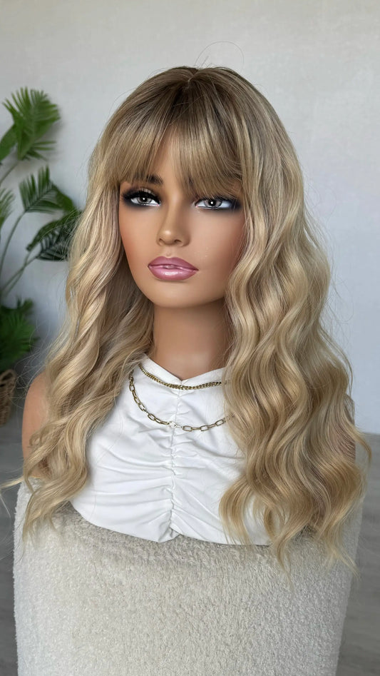 long blonde wavy wig with fringe, darker root to light blonde ends.