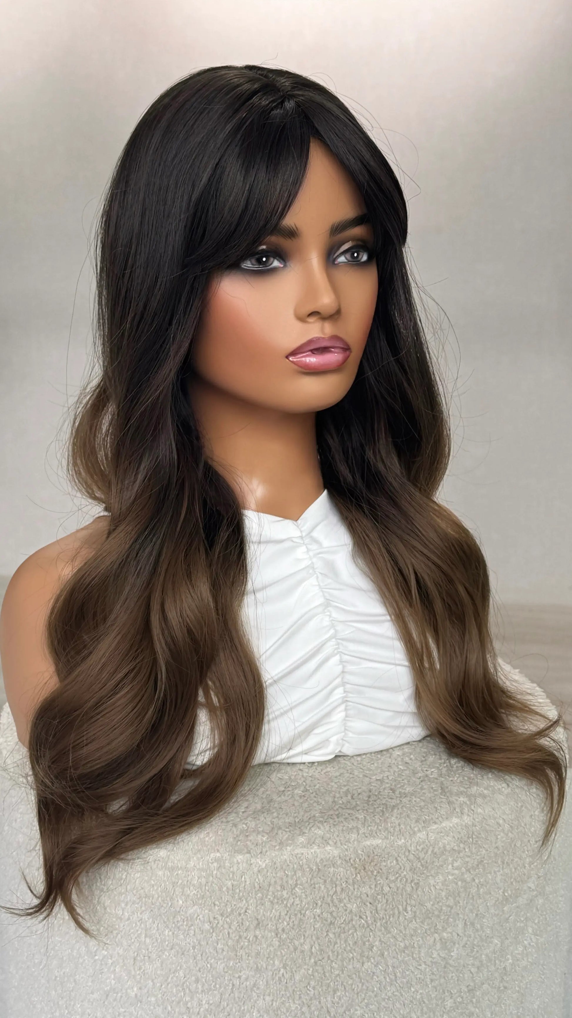 synthetic natural wig from side on, showing length of wavy hair. fringe is parted to the side, natural lighting.