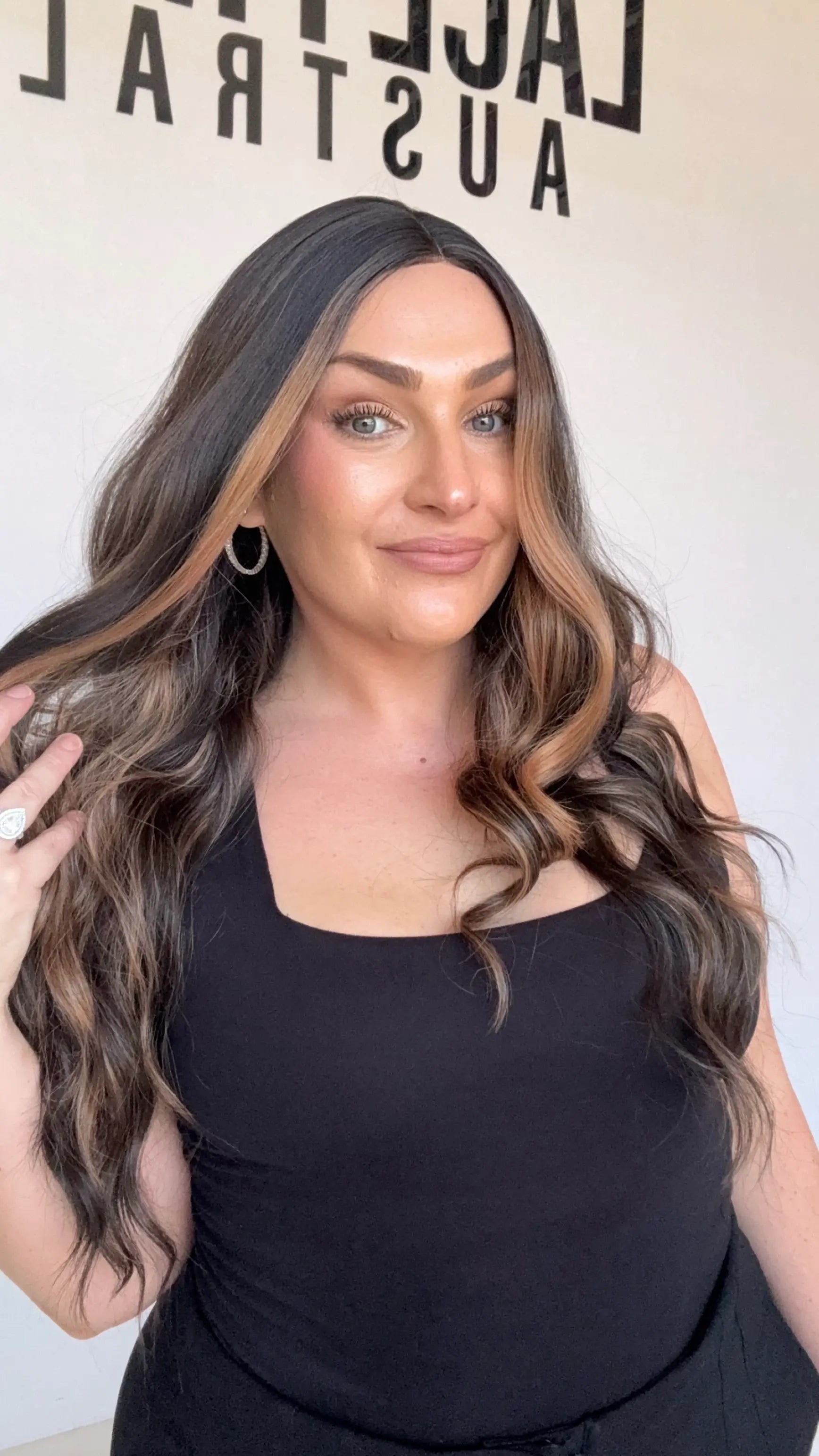 dark brunette wavy synthetic, middle part with face framing highlights.