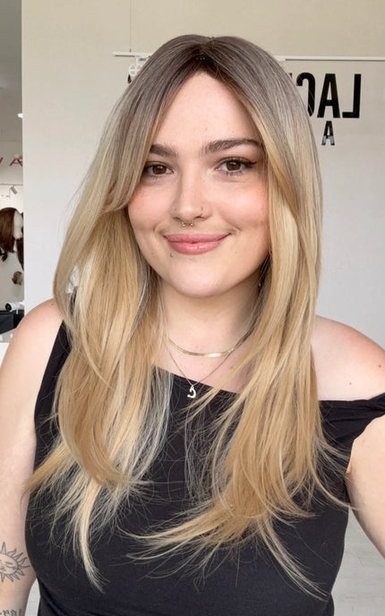 a warm vanilla blonde wig with mid-long length hair. featuring a middle part, long curtain bangs and layers throughout for movement.