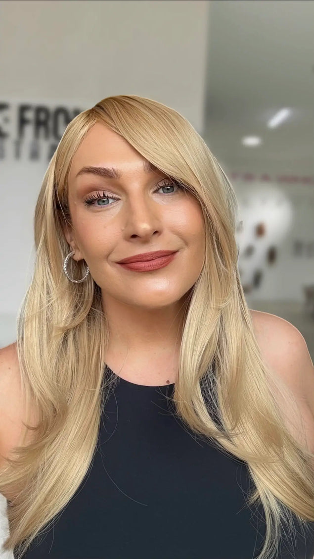 warm golden blonde hair with layers and left side part, medium to long length hair.