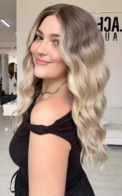 a full density wig, with a beachy wave style and cool toned blonde ombre colour, a glueless wig cap and middle part.