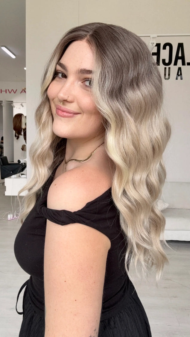 a full density wig, with a beachy wave style and cool toned blonde ombre colour, a glueless wig cap and middle part.